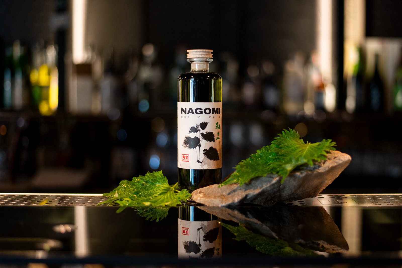 NAGOMI amaro di shiso TSUNO POP sul bancone del bar con foglie di shiso verde fresco